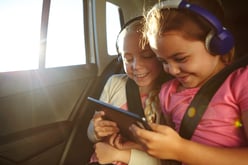 two girls using tablet in the car