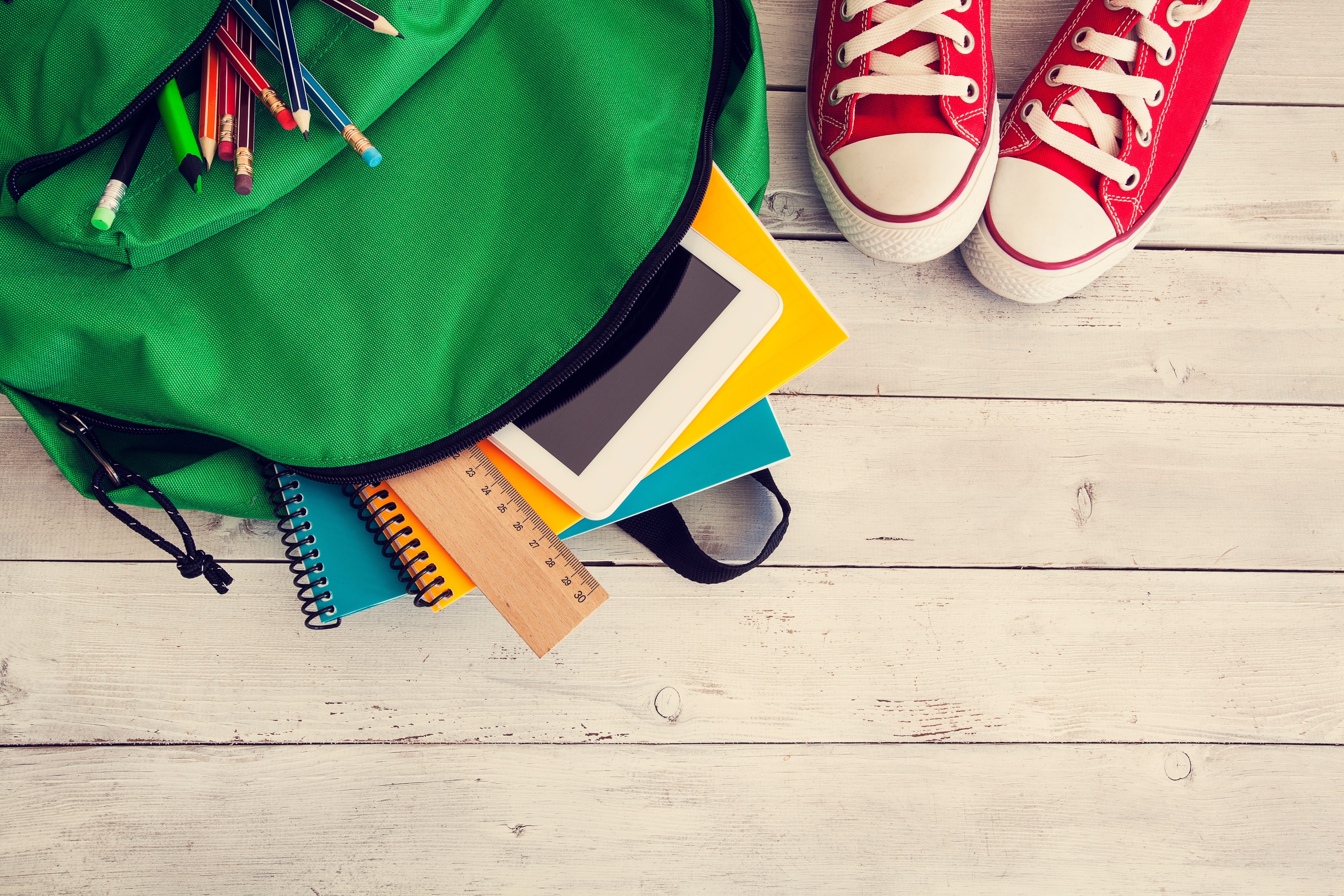 Back to School Background_backpack, converse shoes, wood_iStock-607605540